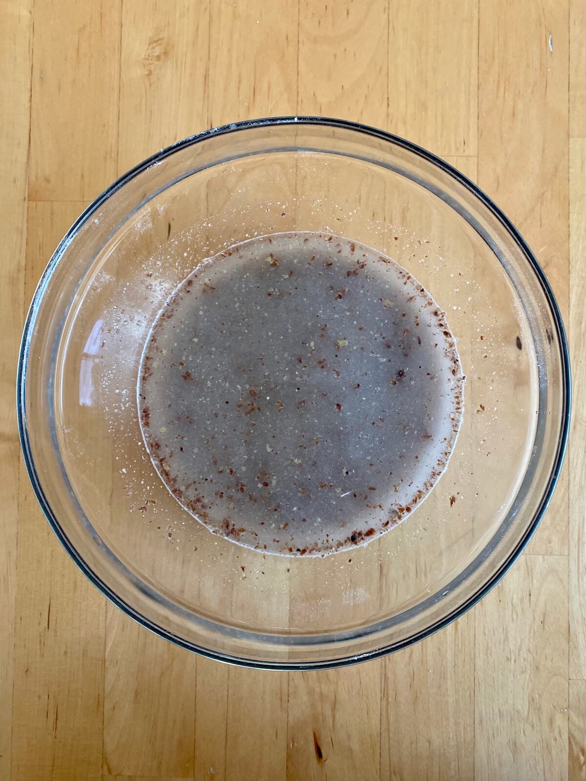 Ground flaxseed and water mixed together in a clear glass bowl.