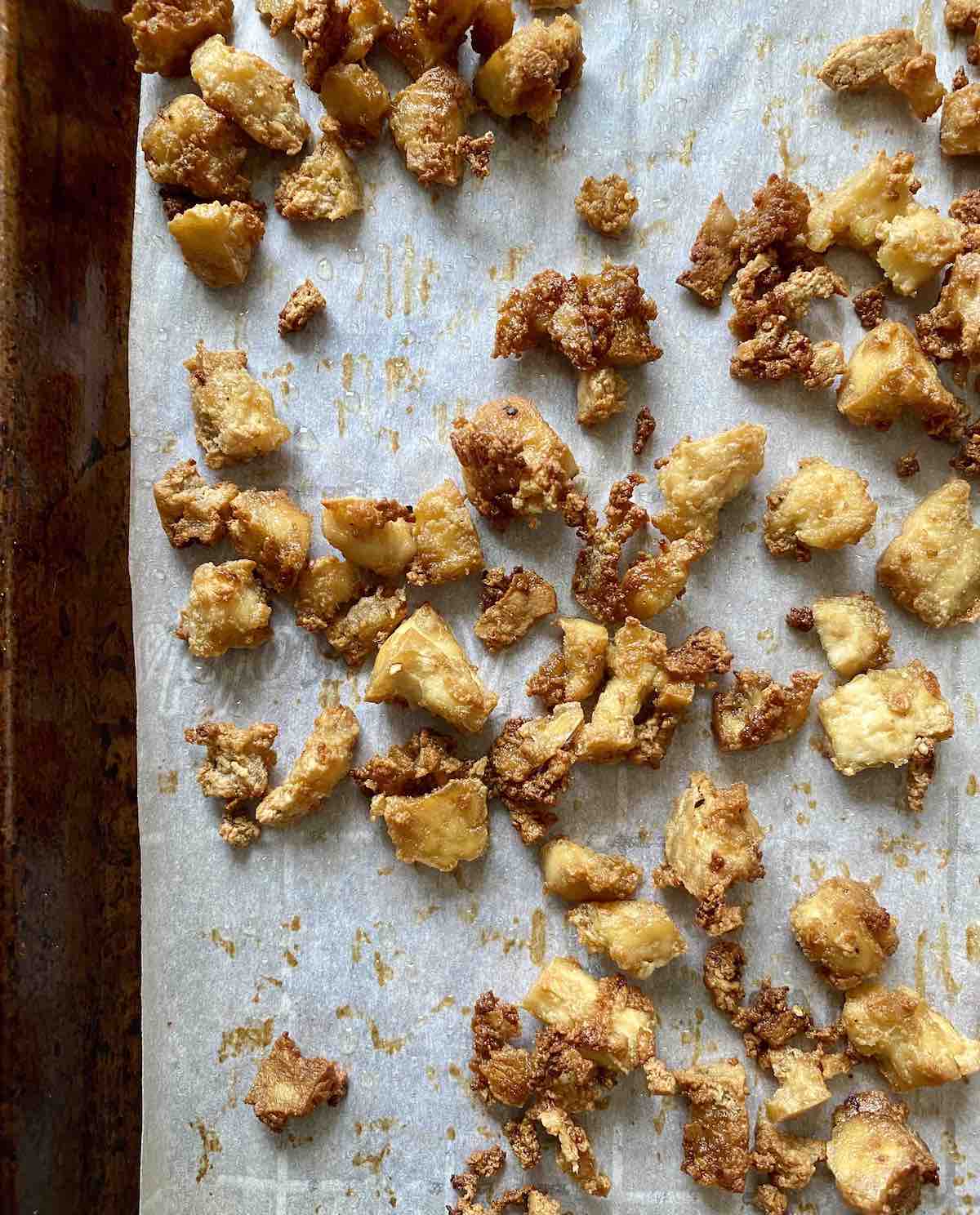 Crispy baked tofu pieces on a baking sheet lined with parchment paper.