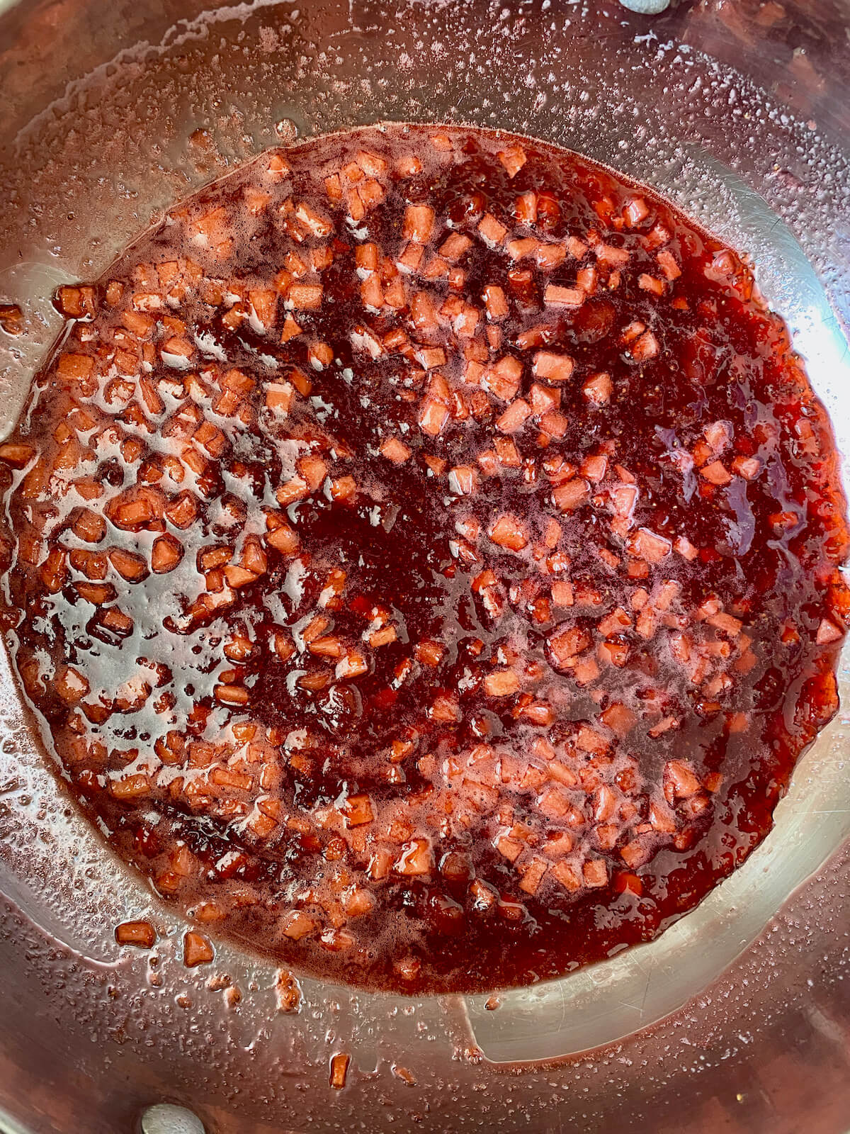 The finished strawberry apple jam in a stainless steel pot.