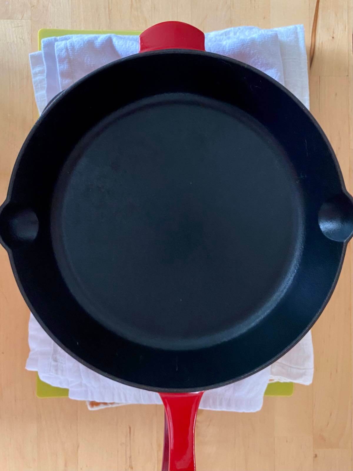 A cast iron pan sitting on top of tofu wrapped in clean kitchen towels.