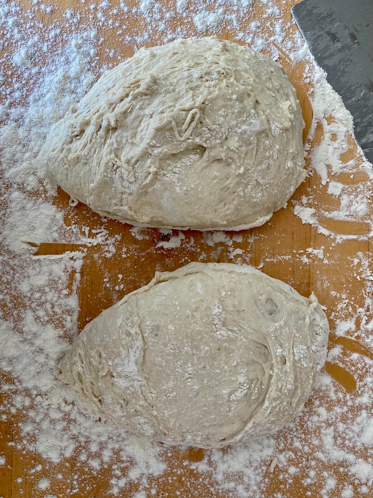 72-hour pizza dough that has just been divided sitting on a floured countertop.