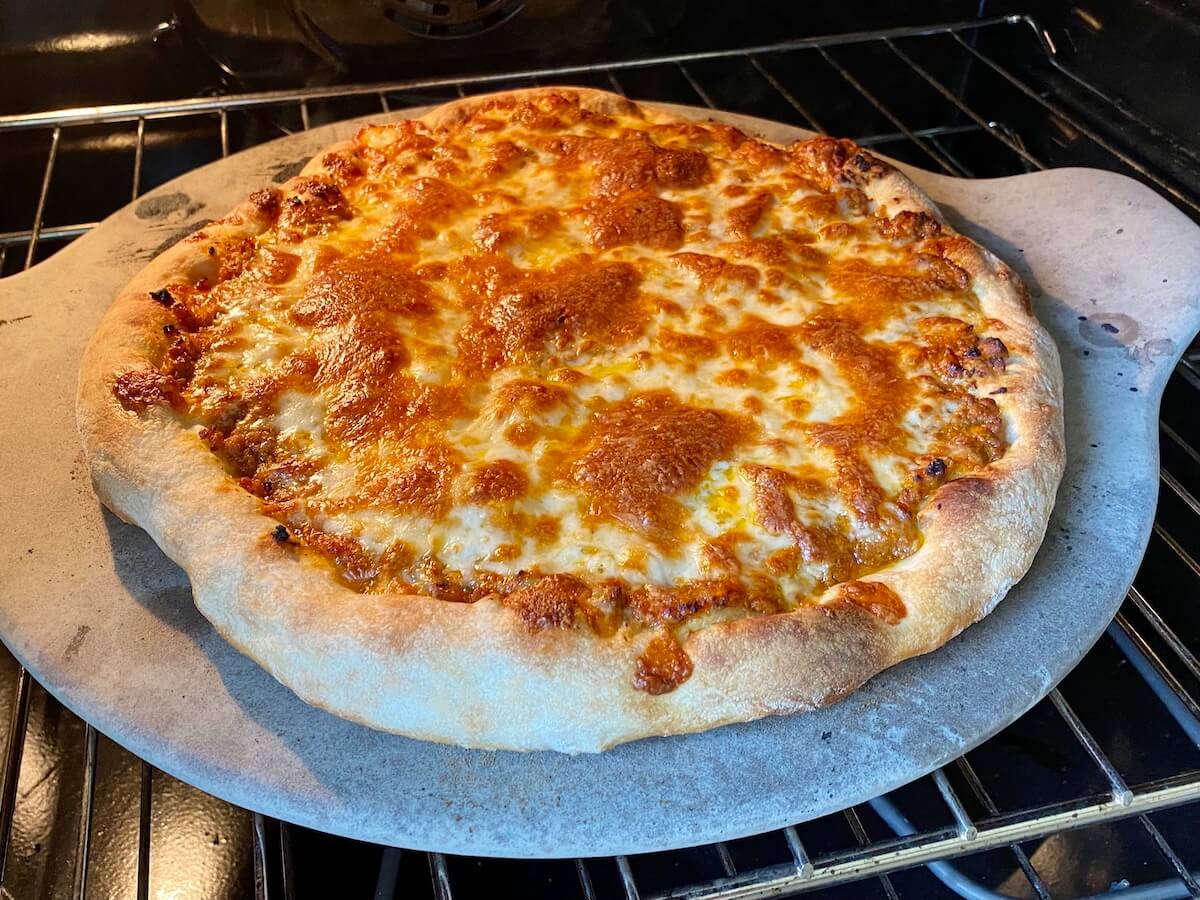 Finished bolognese pizza on a pizza stone inside of the oven.