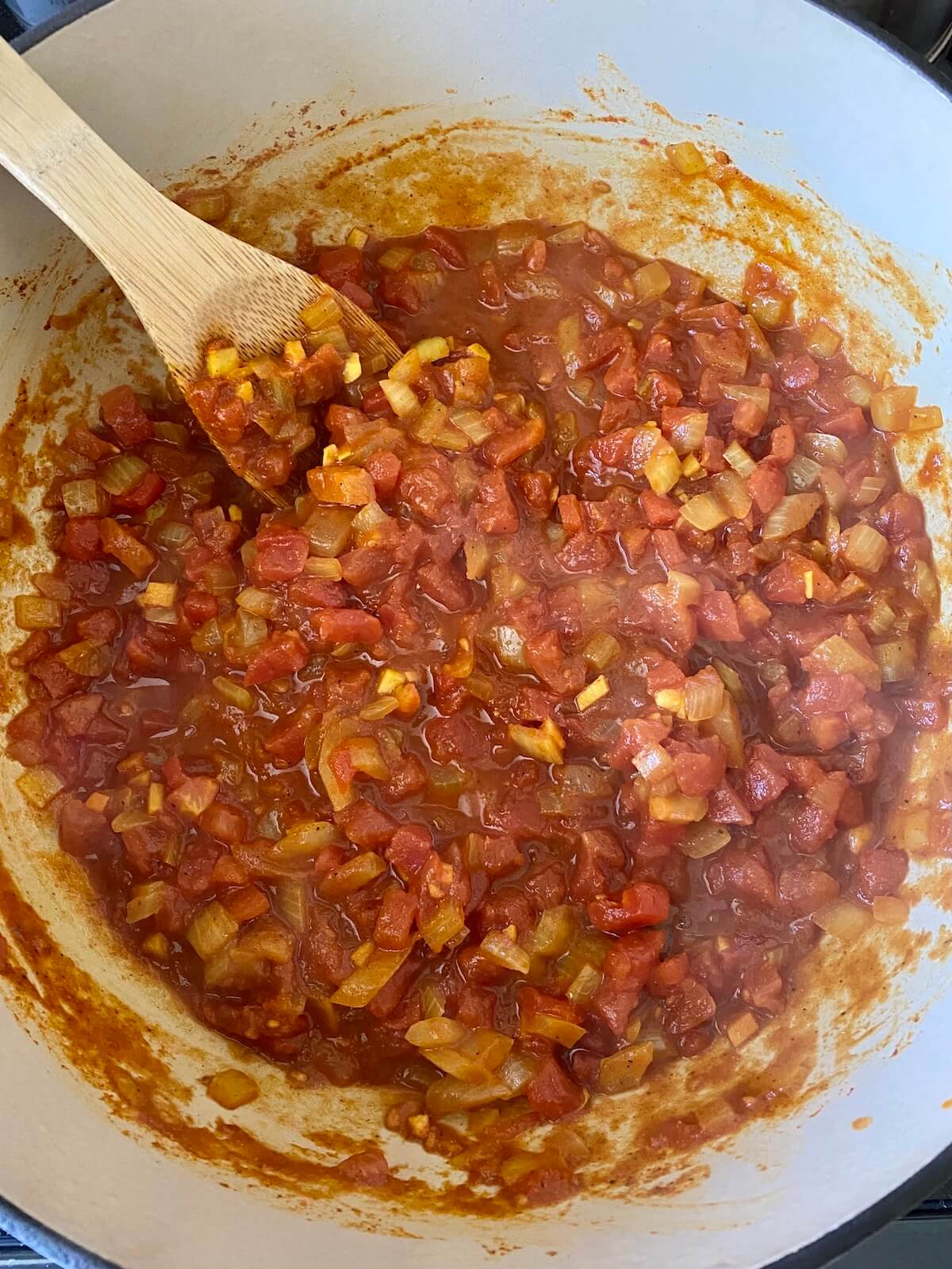 Diced tomatoes with the flavor base simmering in a Dutch oven.