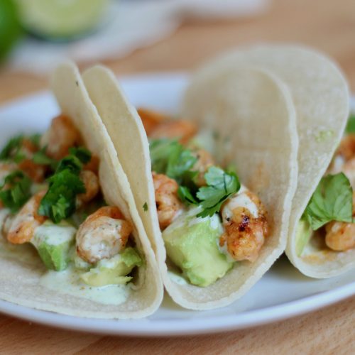 A white plate with three honey chipotle shrimp tacos on it.