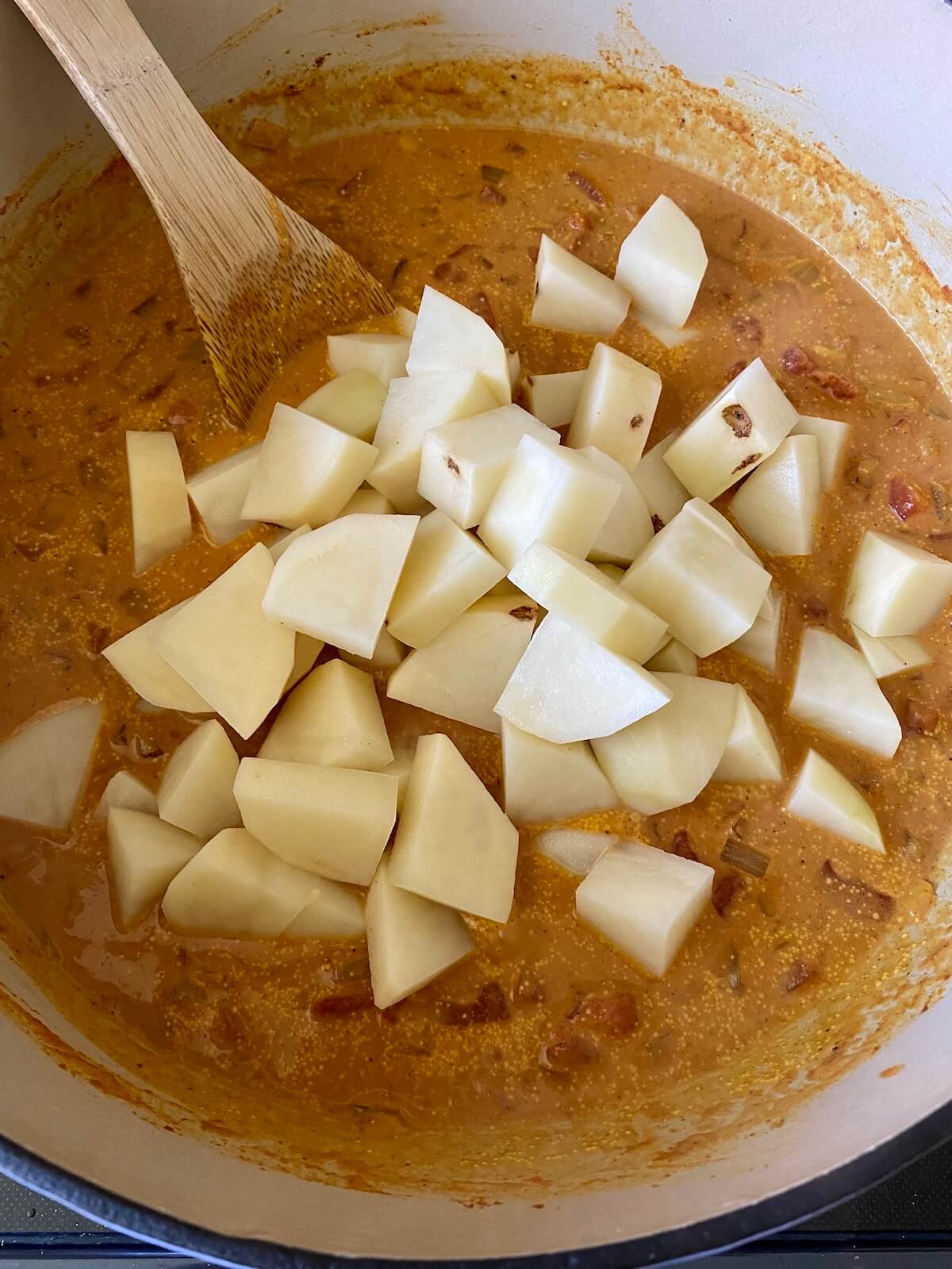 Potatoes added to the tomato and coconut milk tikka masala sauce in the Dutch oven.