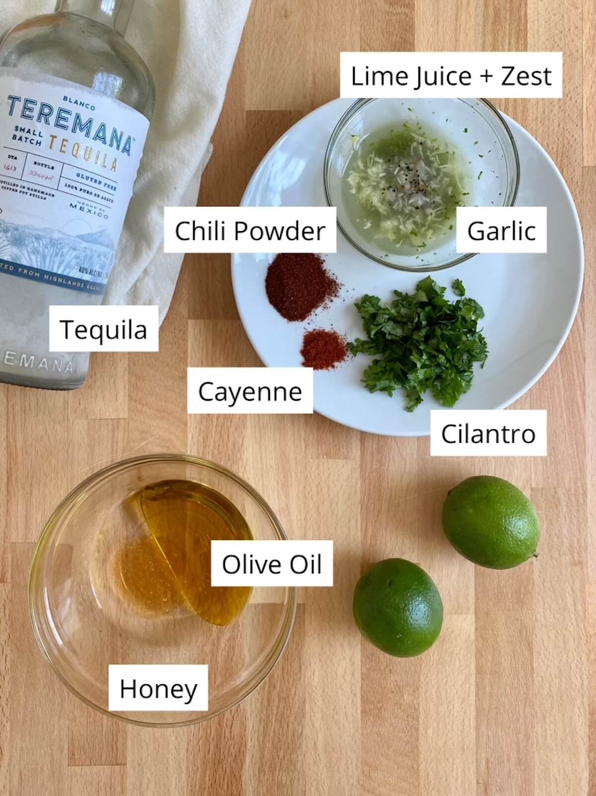 The ingredients to make tequila lime shrimp tacos are displayed on a butcher block countertop.