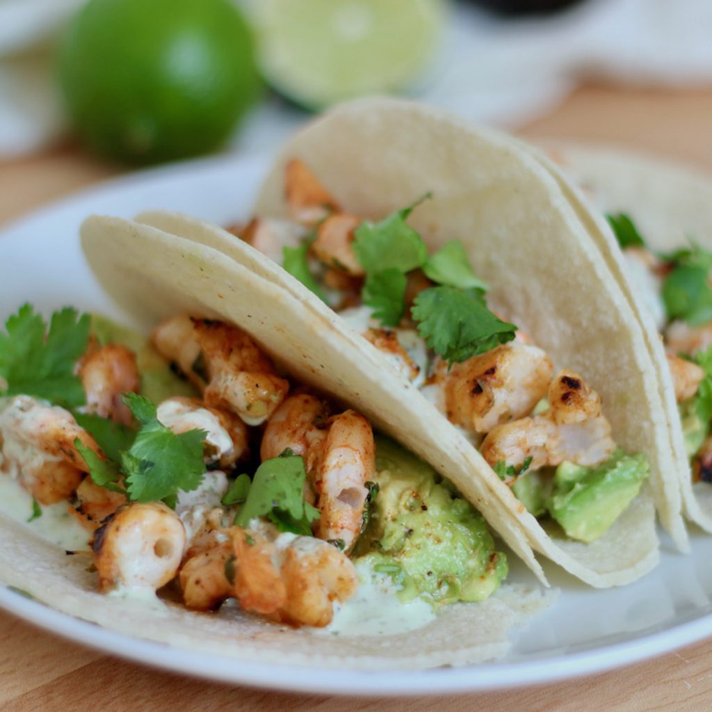 A white plate with three tequila lime shrimp tacos.