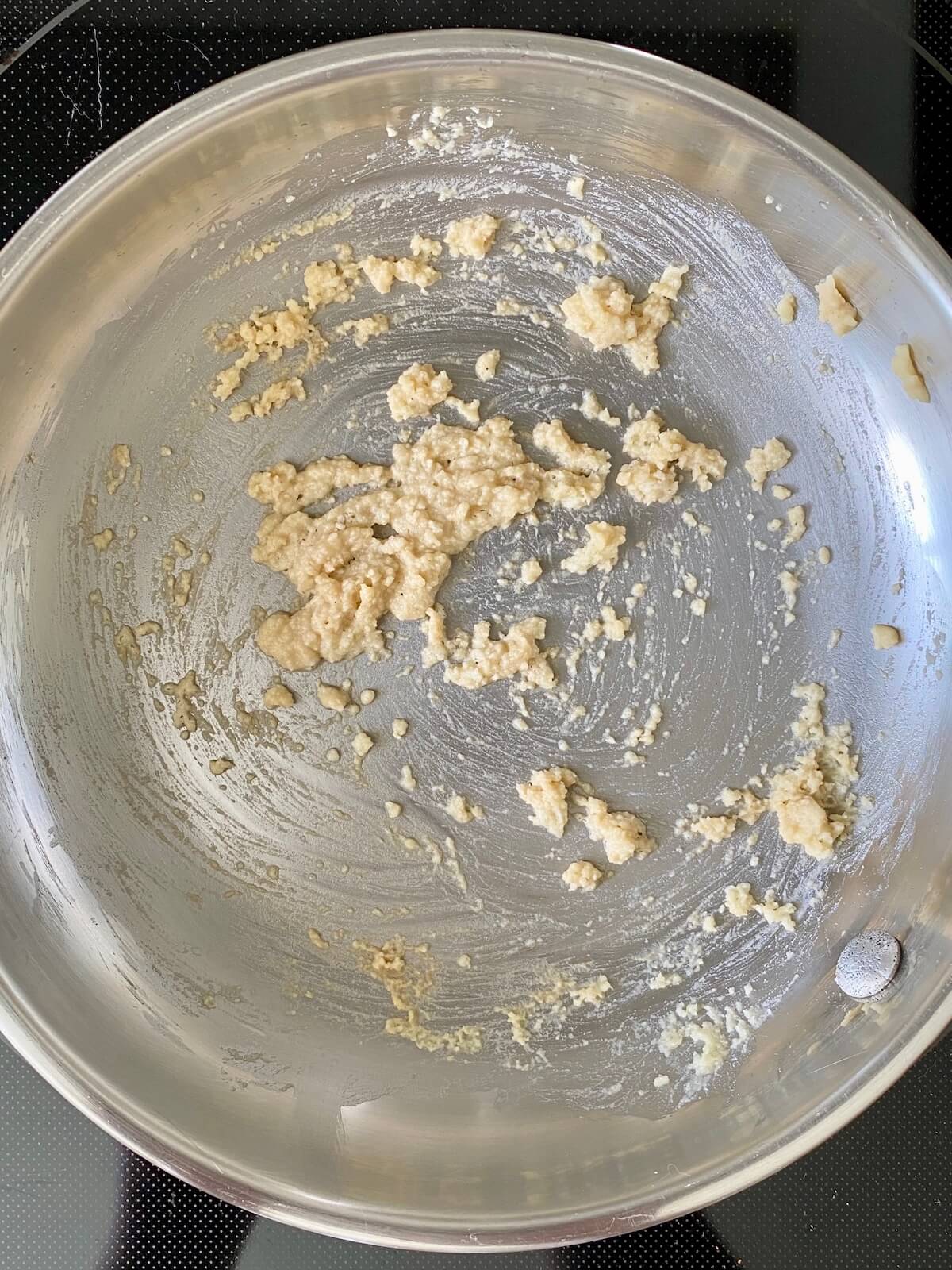 A basic roux of butter and flour in a stainless steel pan.
