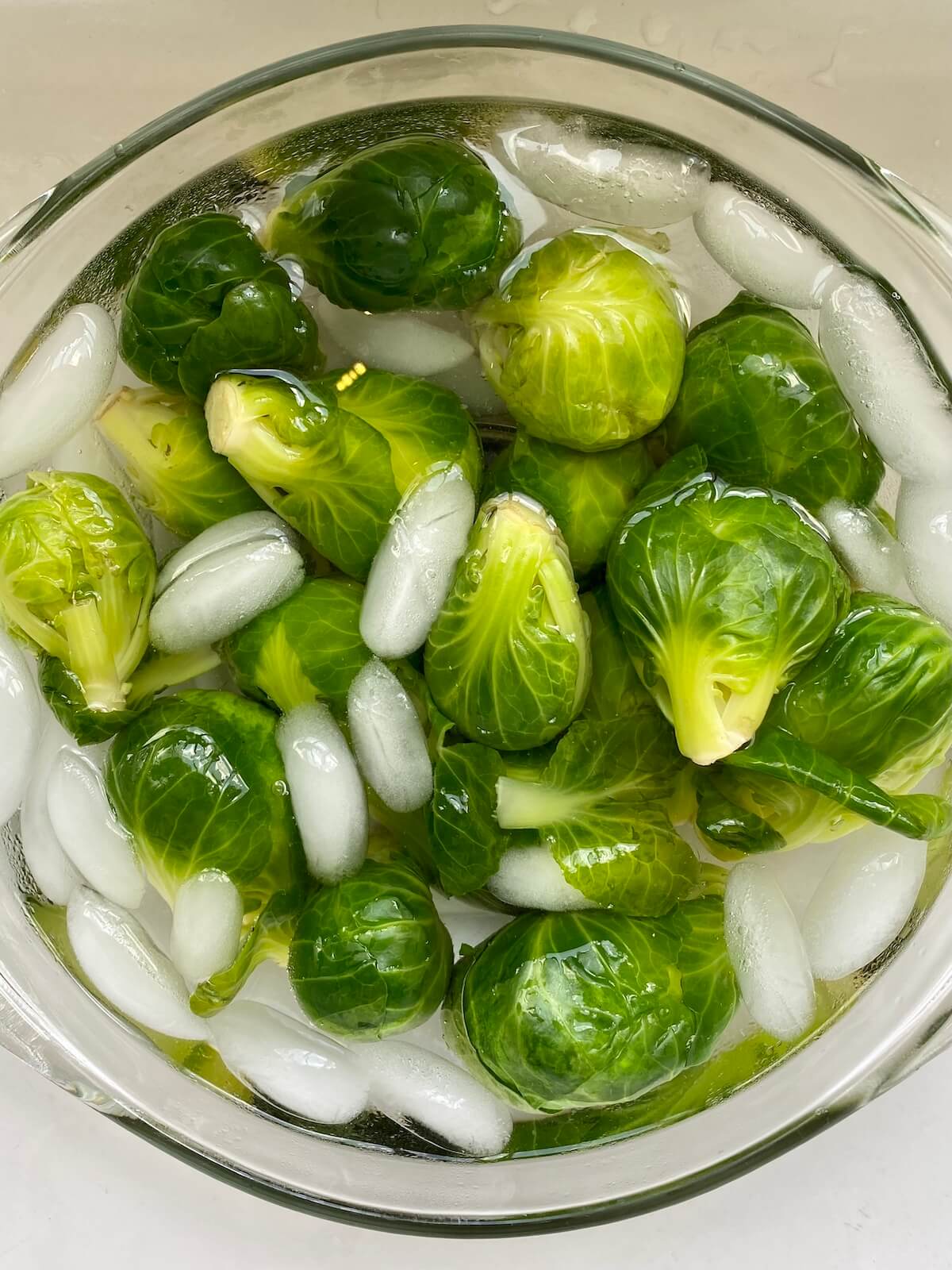 Blanched Brussels sprouts in a bowl of ice water.