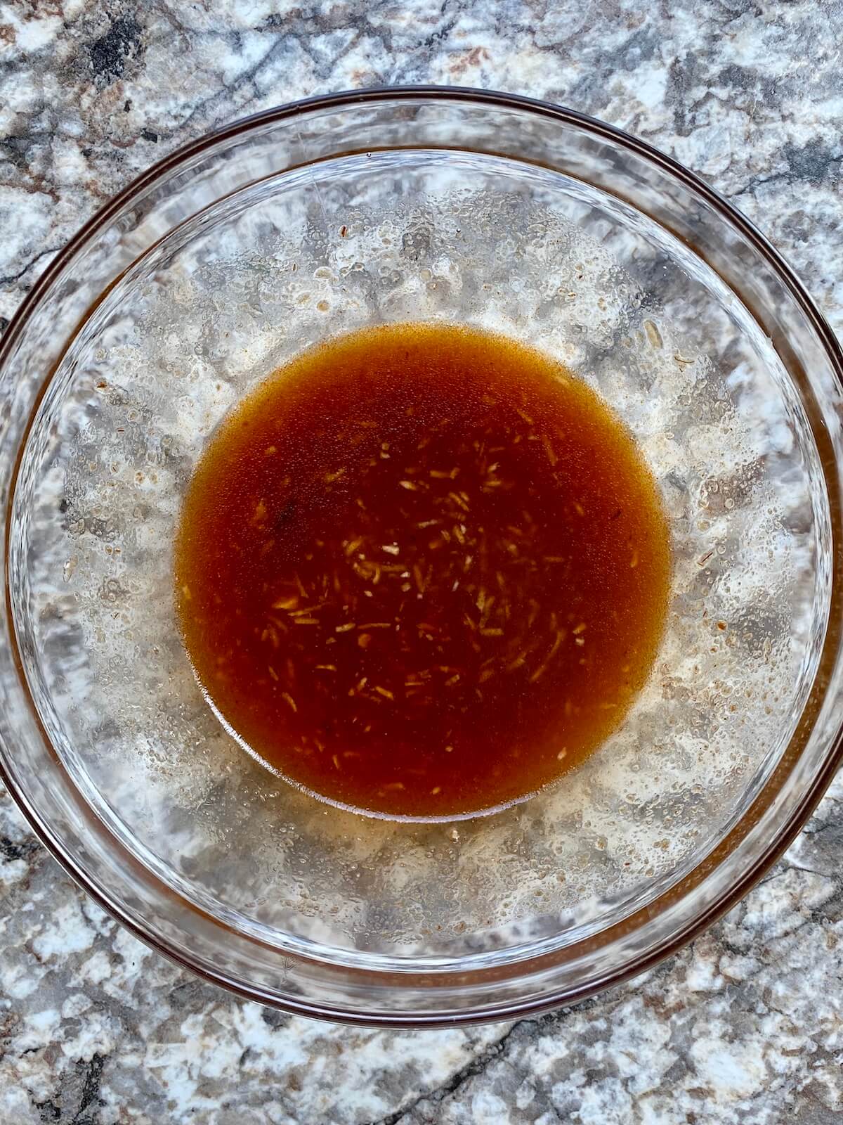A clear bowl with honey chipotle marinade in it.