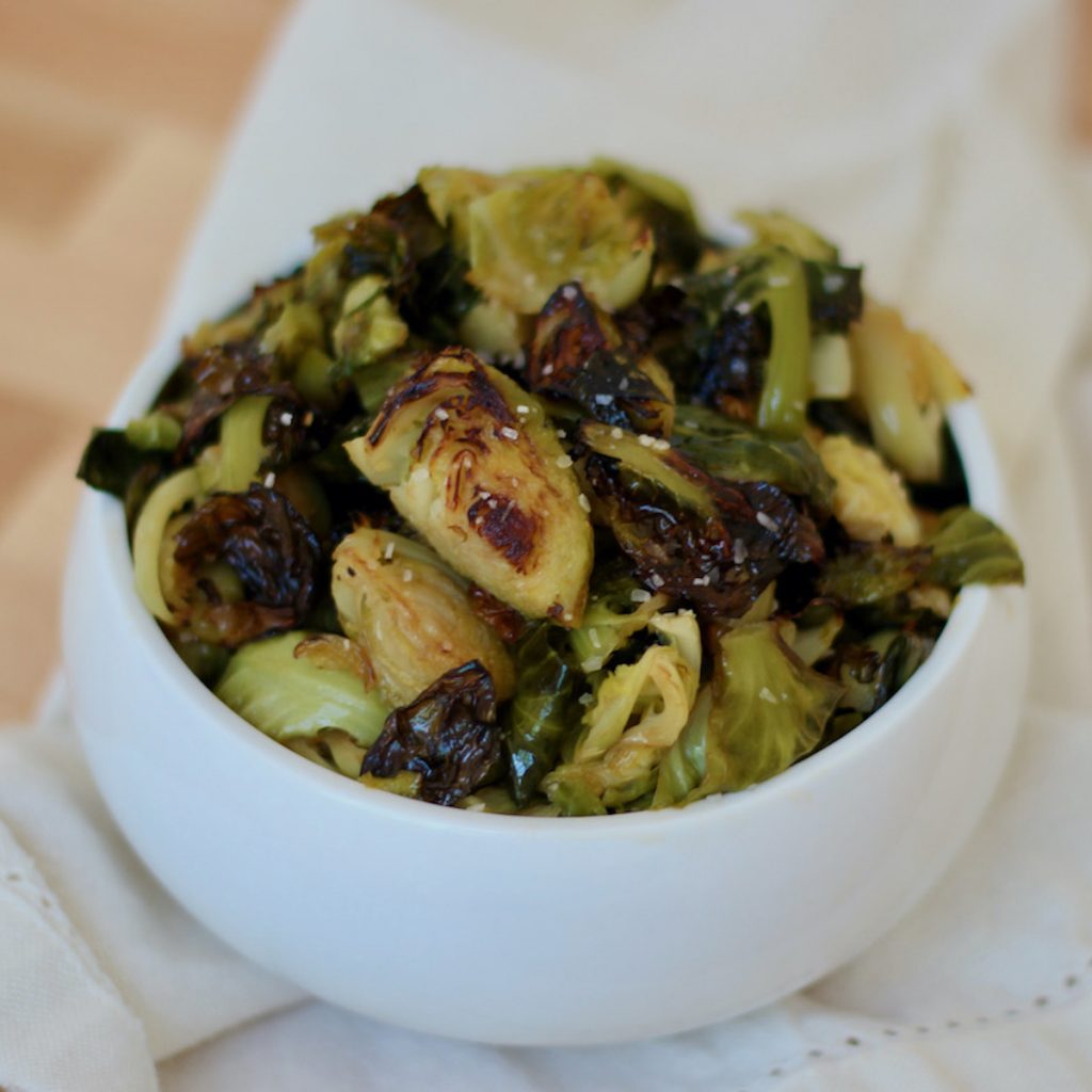 A white bowl filled with crispy roasted longhorn brussels sprouts.