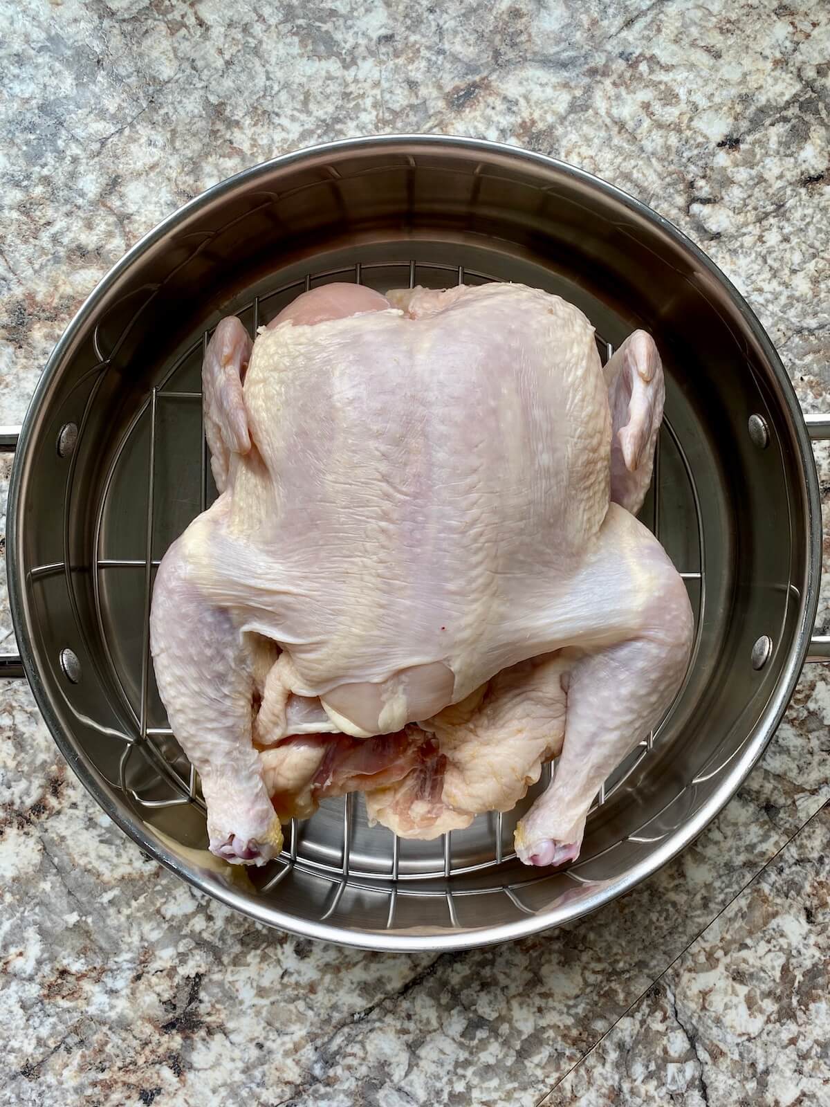 A whole chicken in a roasting pan.