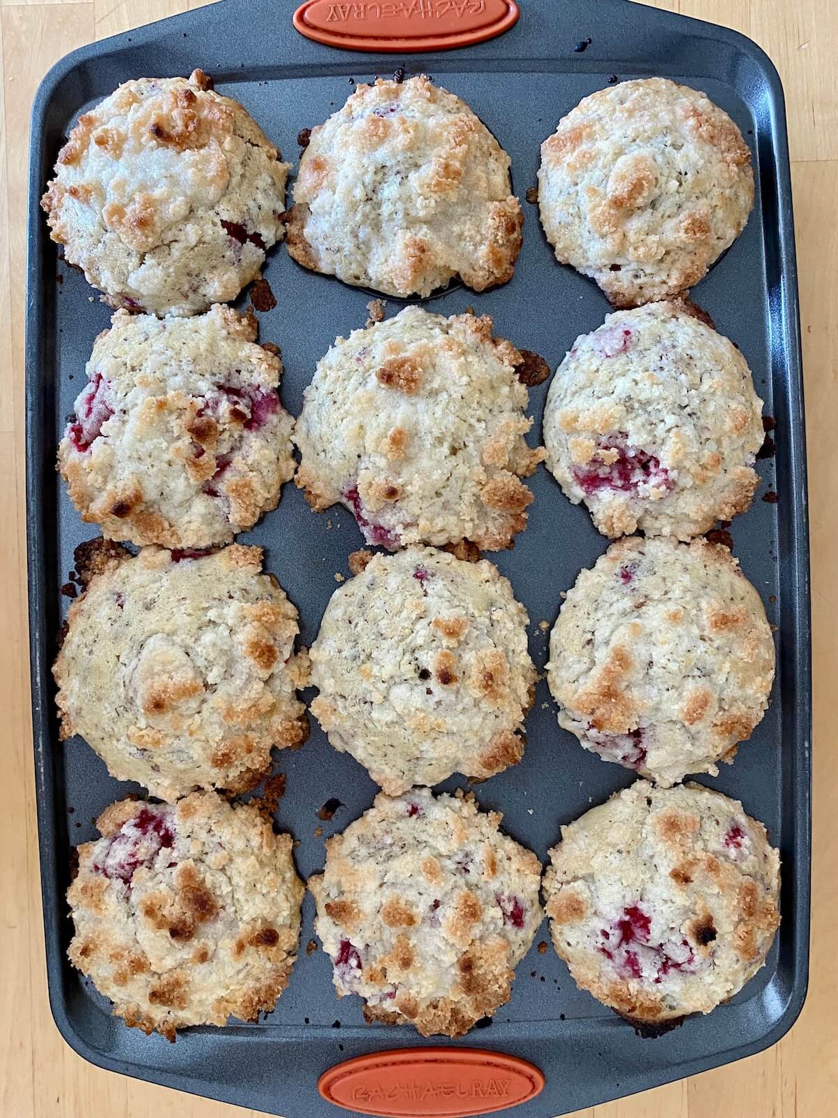 A 12-cup muffin tray with 12 baked raspberry vegan muffins.