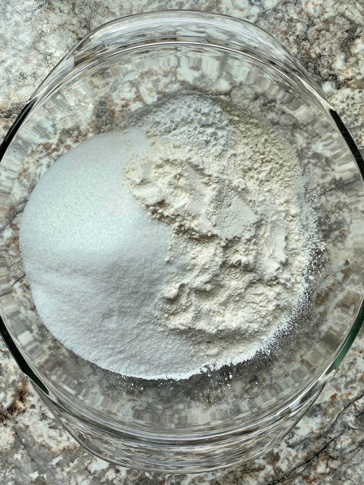 Flour, sugar, salt, and baking powder in a clear glass bowl.