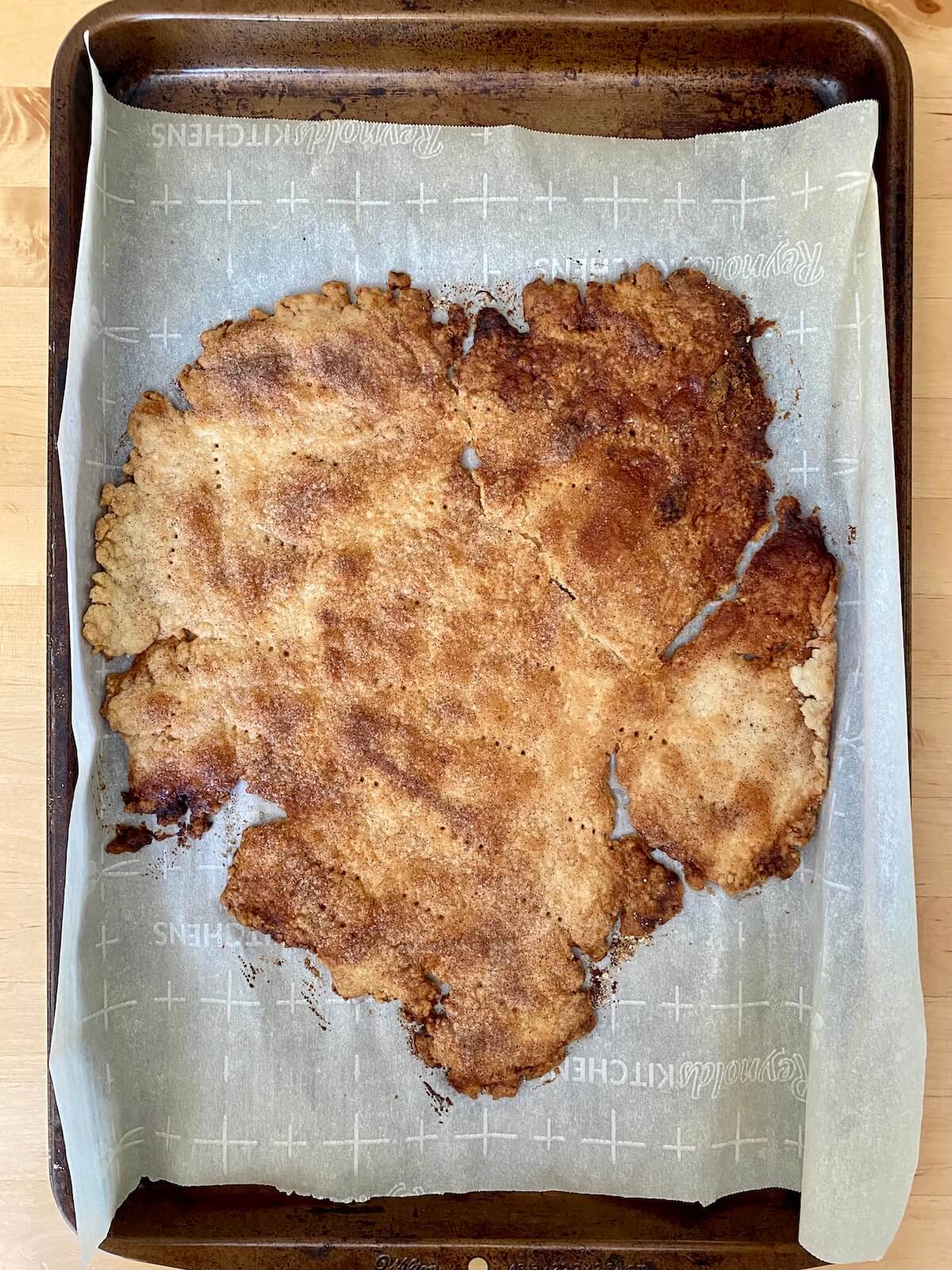 A cinnamon-sugar pie crust baked to golden brown perfection on a baking sheet.
