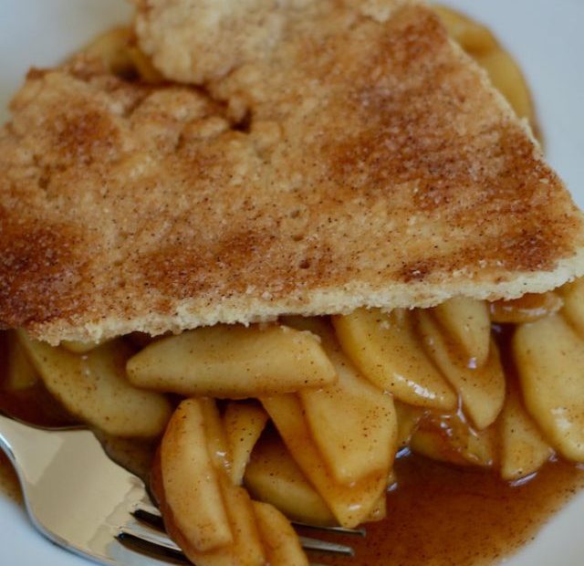 A slice of deconstructed apple pie with a fork digging into some of the apples.