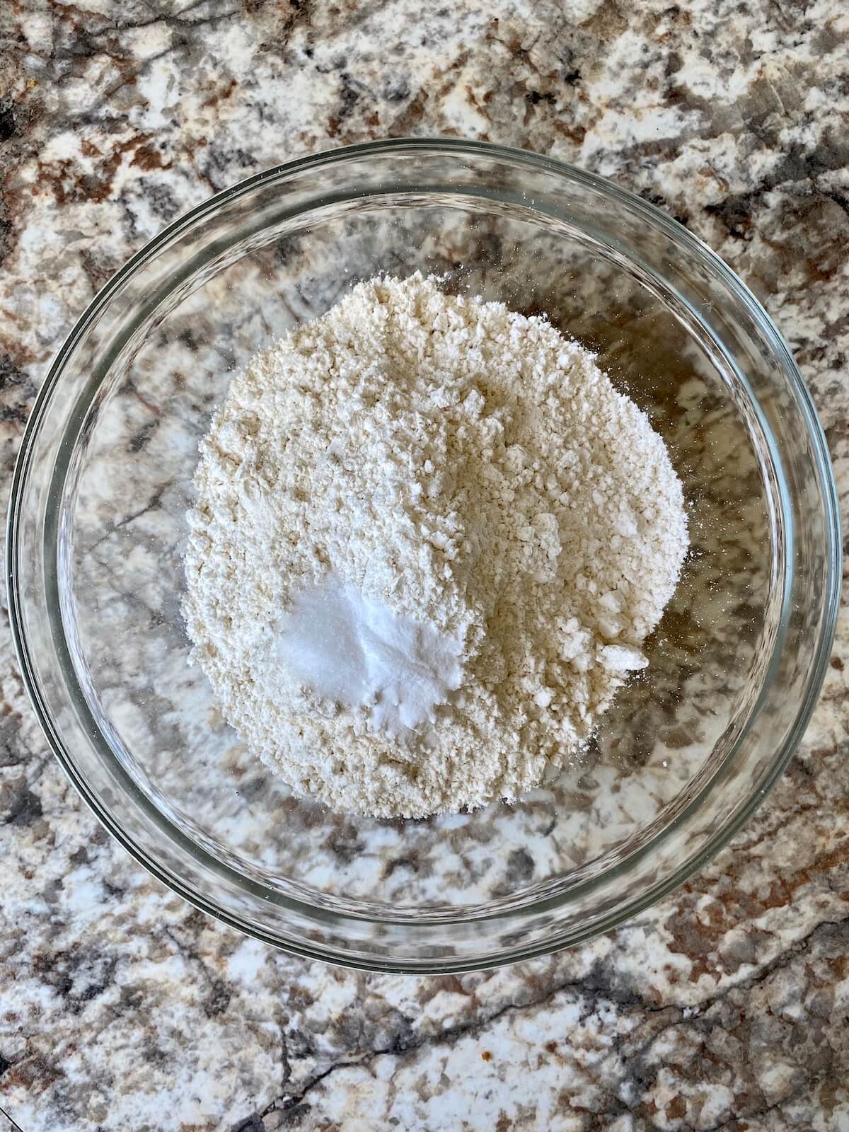 Flour, baking soda, and salt in a clear glass mixing bowl.