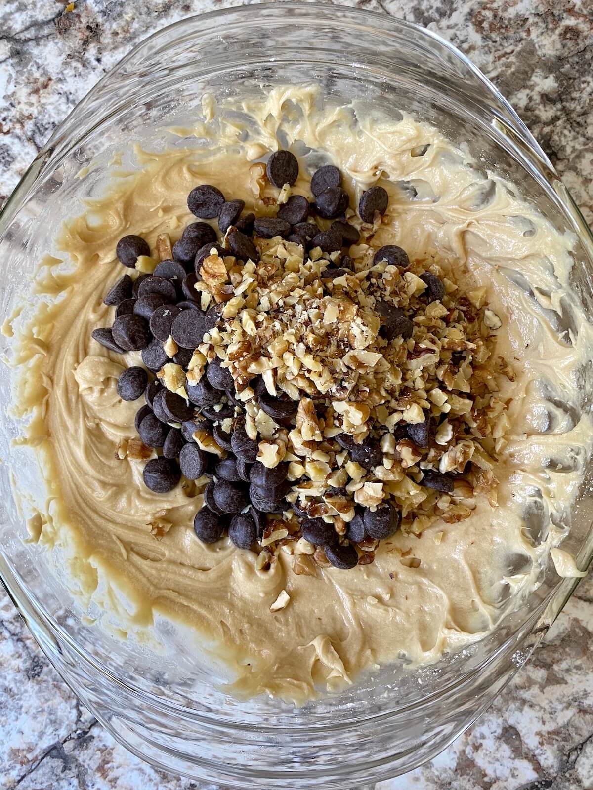 The cookie batter with chocolate chips and walnuts on top, prior to being fully mixed in.