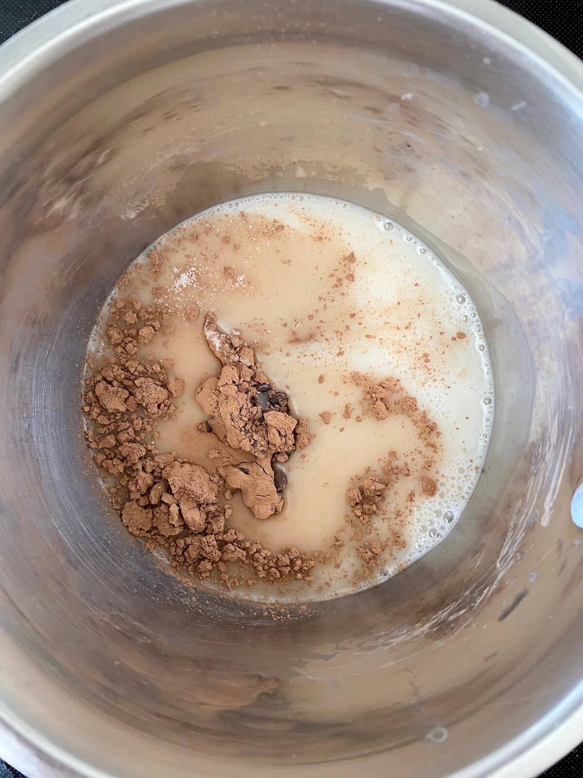Oat milk, sugar, cocoa powder, and chocolate chips in a small, stainless steel saucepan before being whisked together.