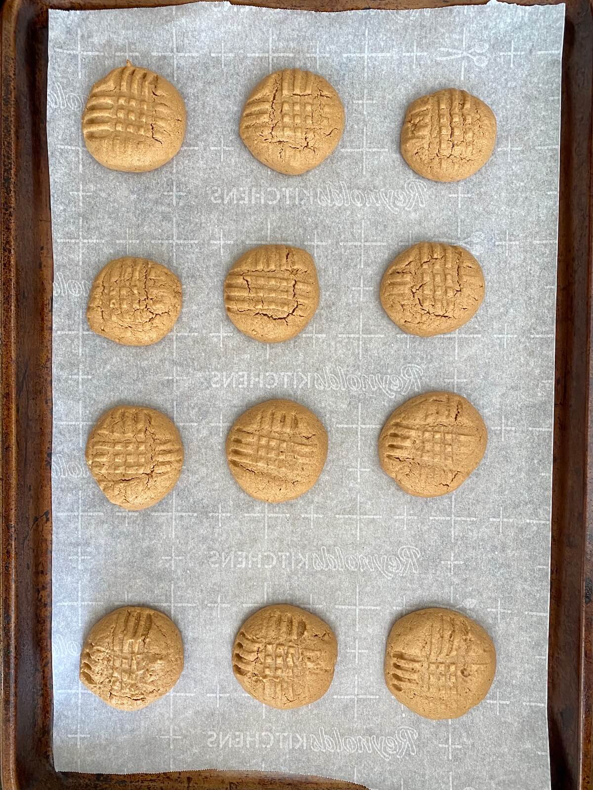 Baked 2 ingredient peanut butter cookies on a parchment-lined baking sheet.