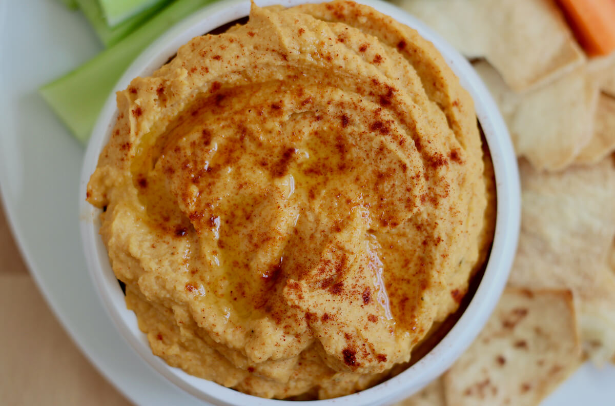 A bowl of smoky butternut squash hummus from above. The hummus is dusted with smoked paprika and drizzled with olive oil.