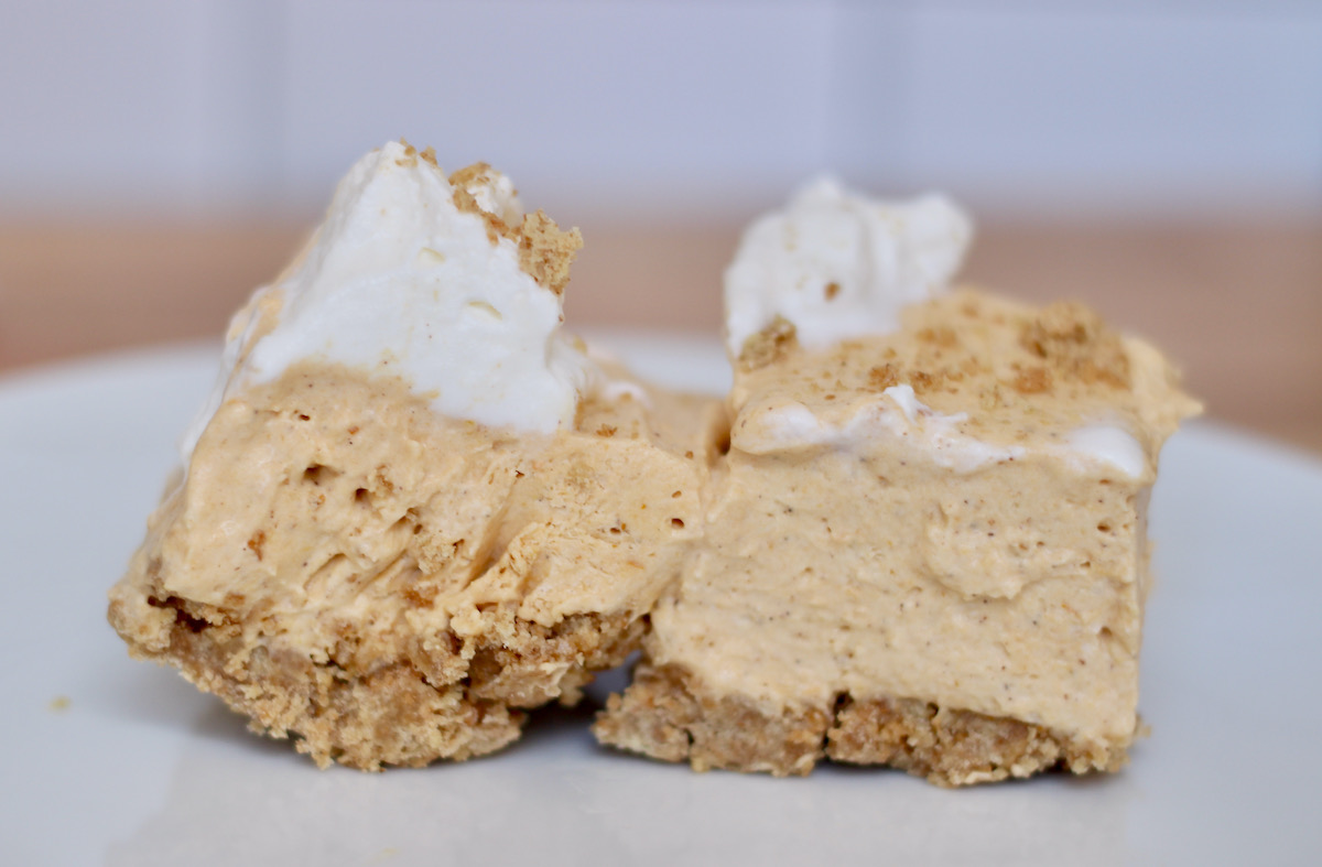 Two small no bake pumpkin cheesecake squares on a white plate.