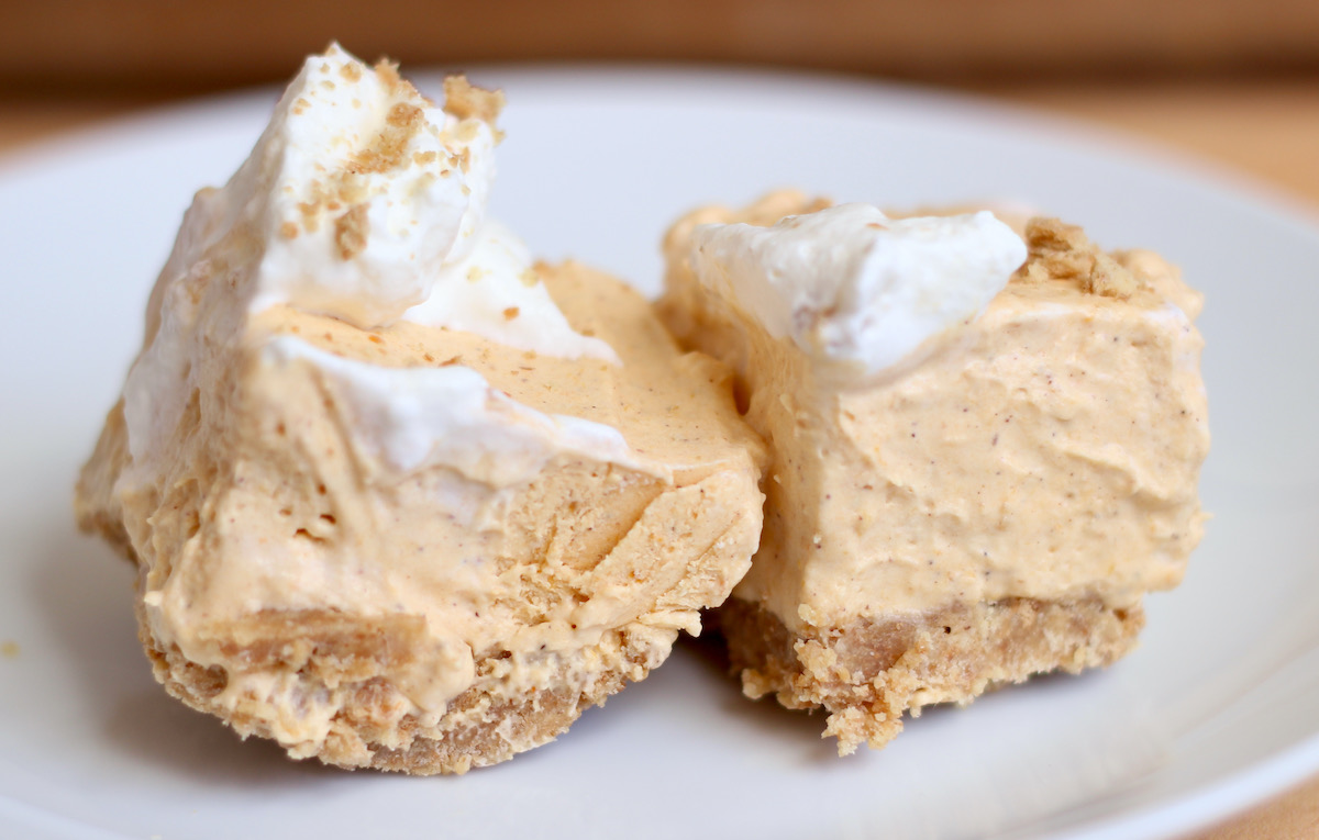 Two no bake pumpkin cheesecake bars on a small white plate.