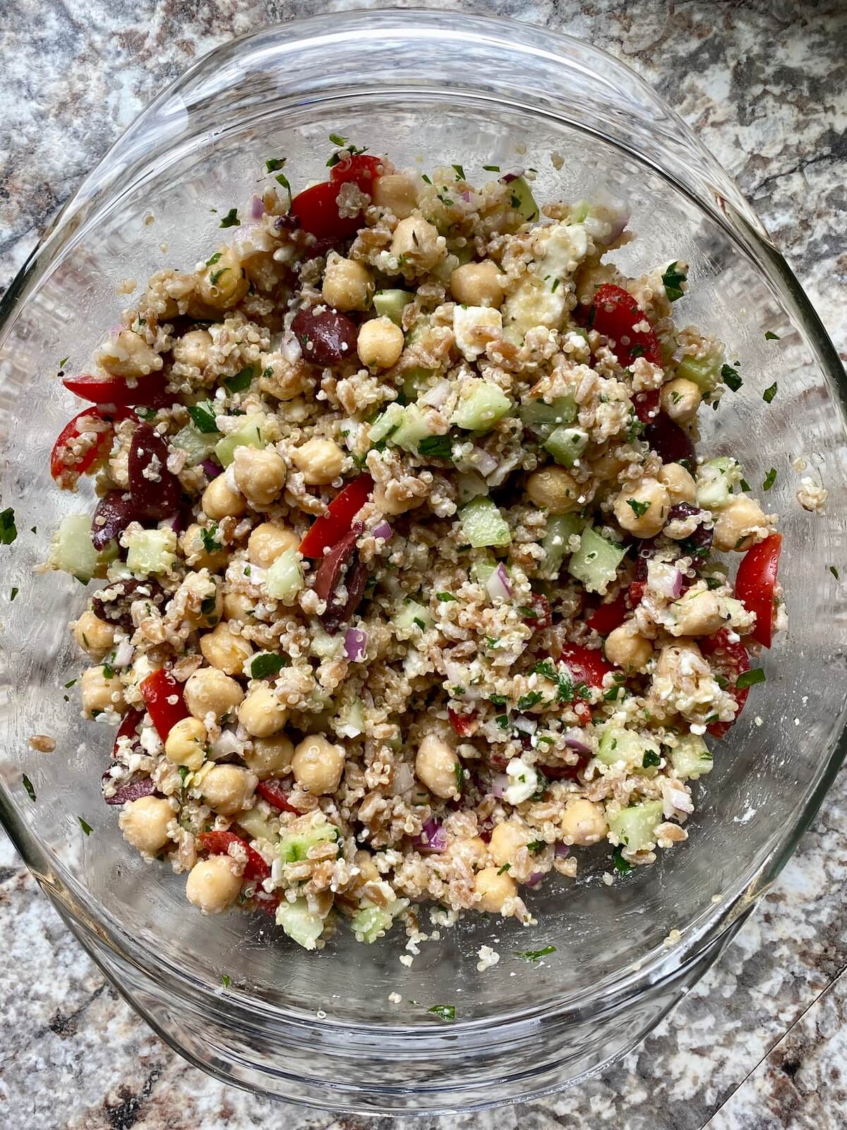 A clear glass bowl filled with ancient grain salad.