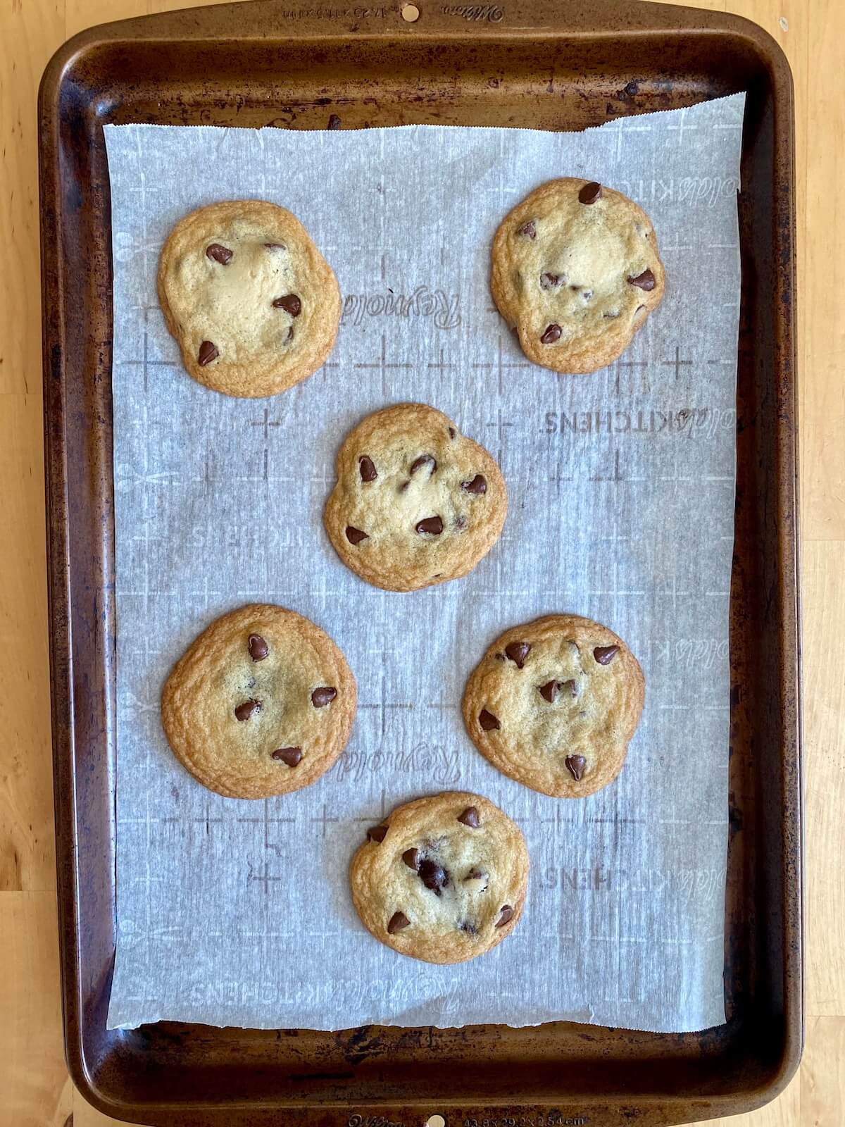 A parchment-lined baking sheet with baked chocolate filled cookies.