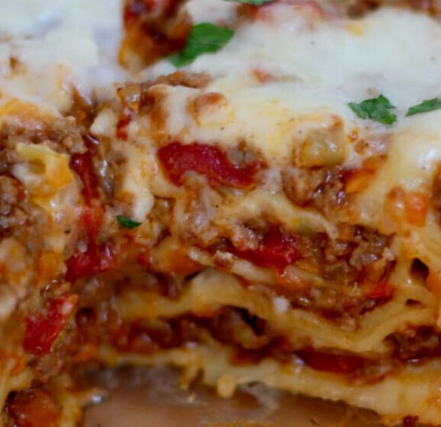 A baking dish filled with lasagna bolognese. A piece of lasagna is missing so you can see the layers.