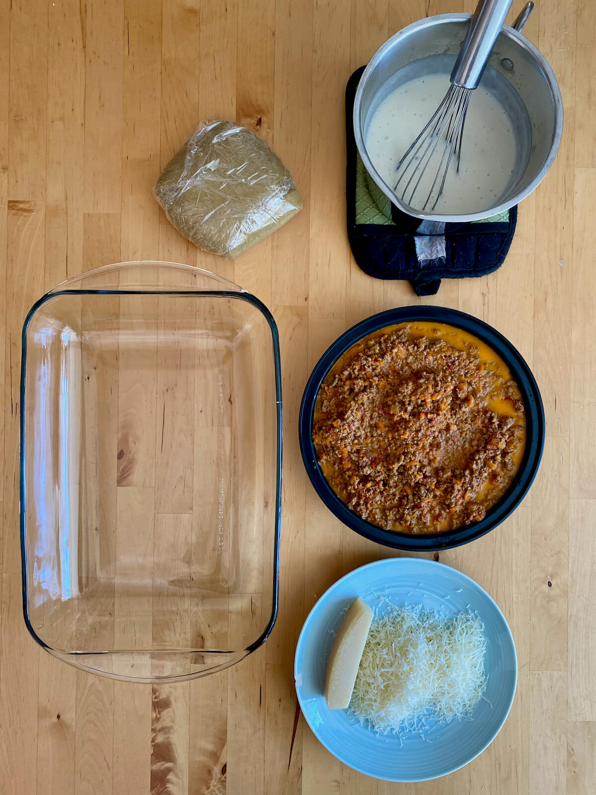 The components to make the lasagna laid out on the counter ready to be assembled in a glass baking dish.