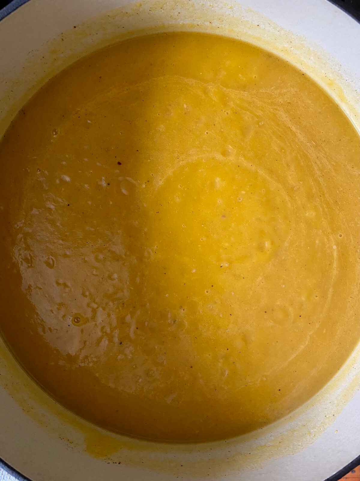 A large Dutch oven filled with simmering pumpkin soup.