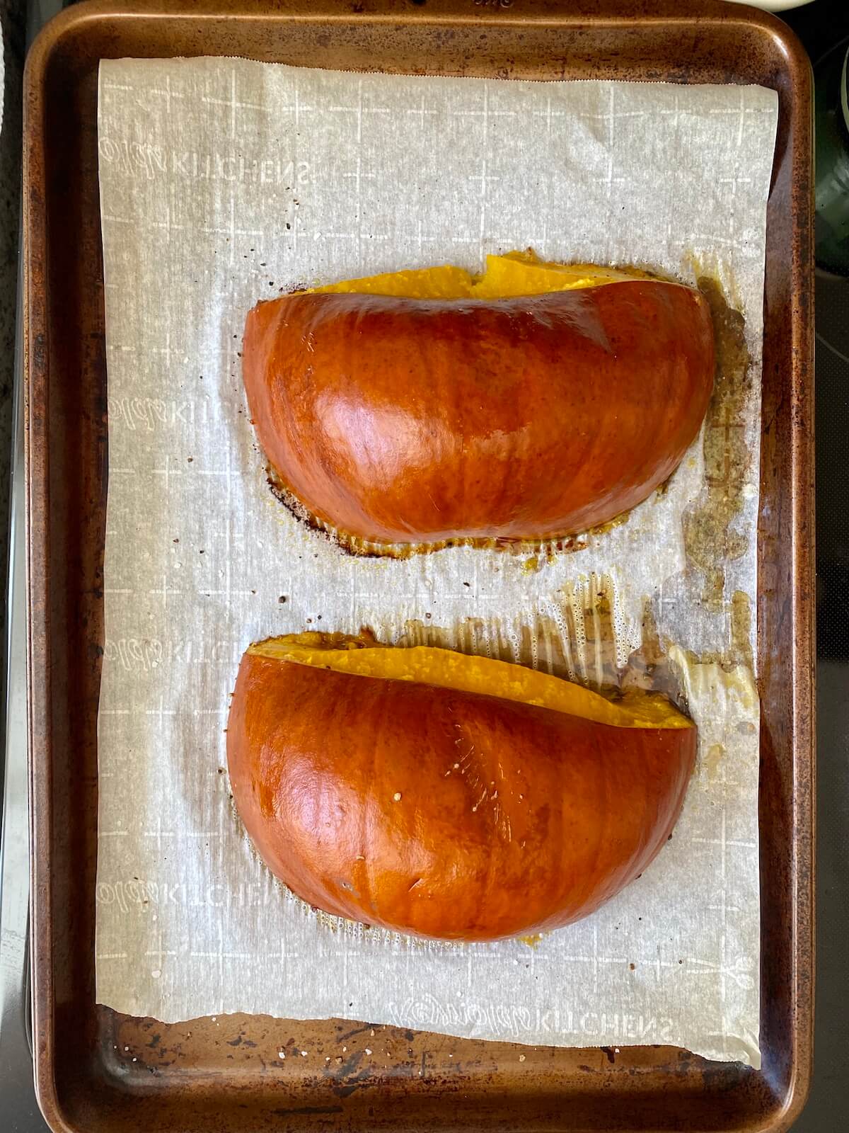 A roasted sugar pumpkin on a parchment-lined baking sheet.