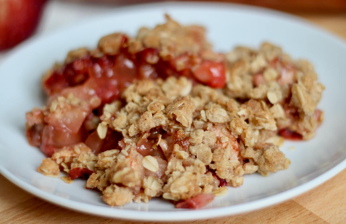 A serving of strawberry apple crisp on a small white plate.