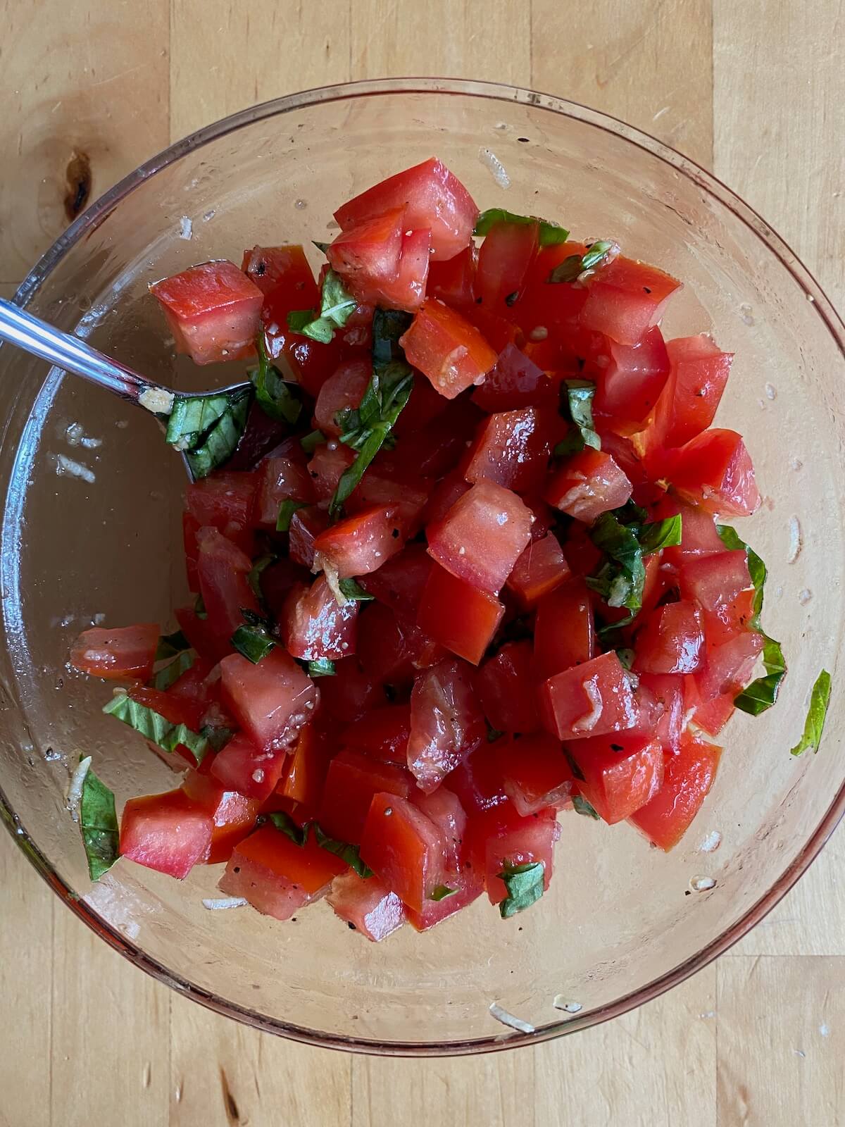 The tomato basil mixture marinated in a glass bowl.
