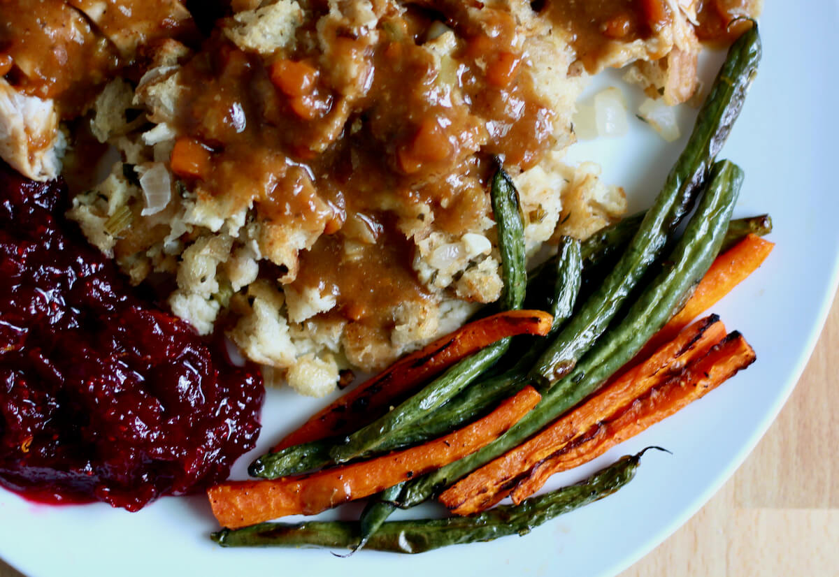 Roasted green beans and carrots as a side dish on a plate of turkey dinner.