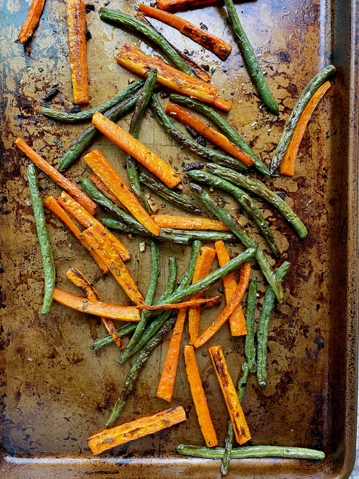 Roasted green beans and carrots on a rimmed baking sheet.