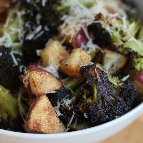 A bowl filled with roasted potatoes and broccoli.
