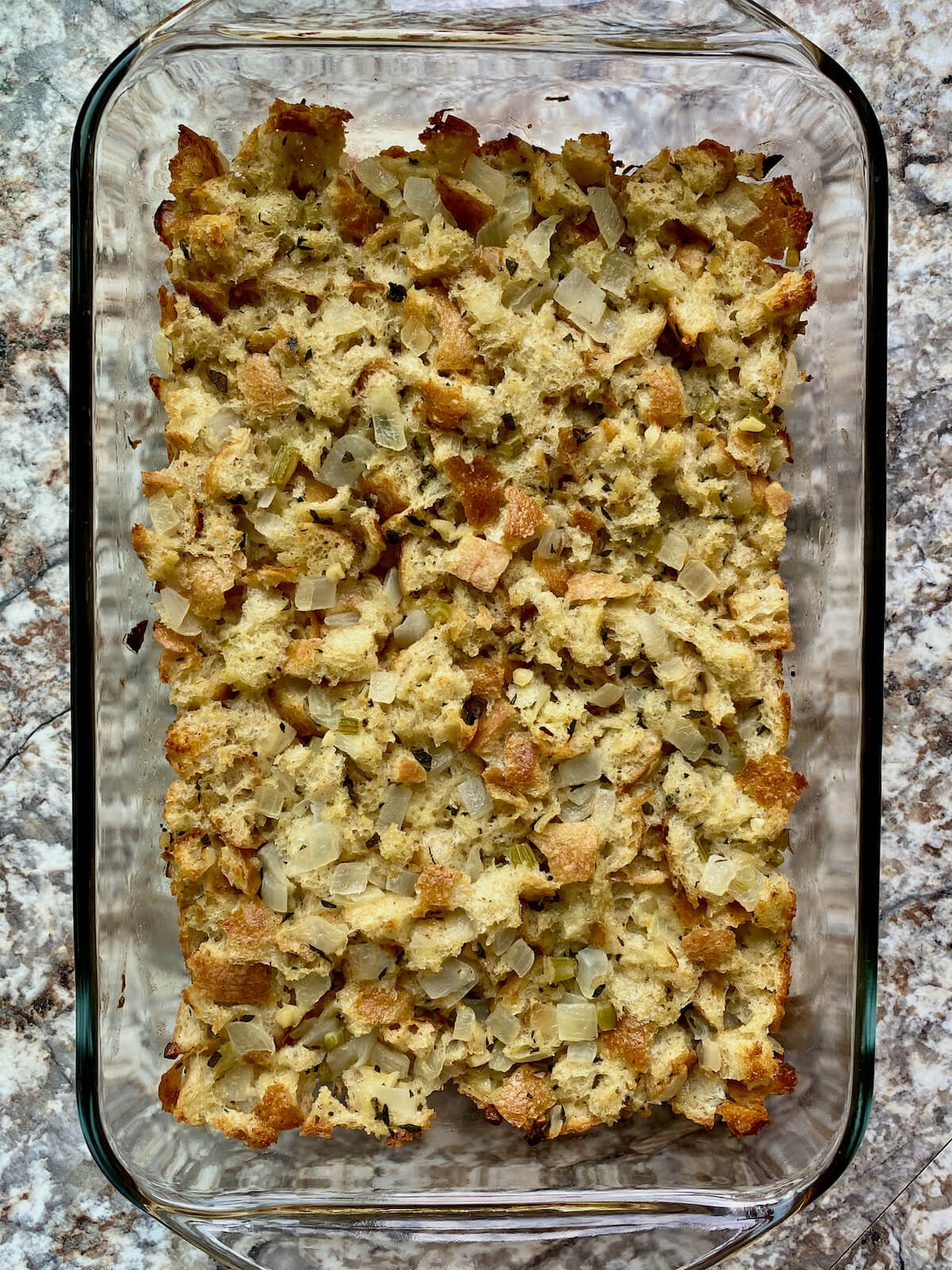Cooked sourdough stuffing in a clear glass baking dish.