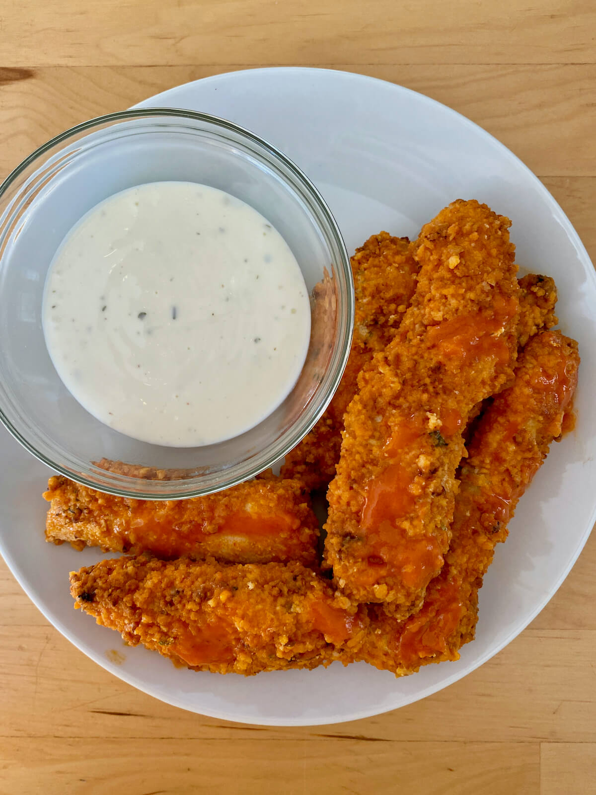 Air fryer chicken tenders after being coated in buffalo sauce.