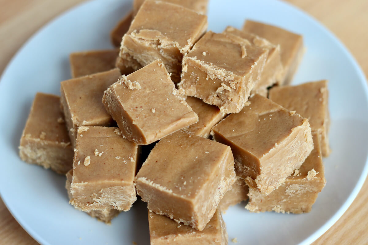 Squares of no bake peanut butter fudge on a small white plate.