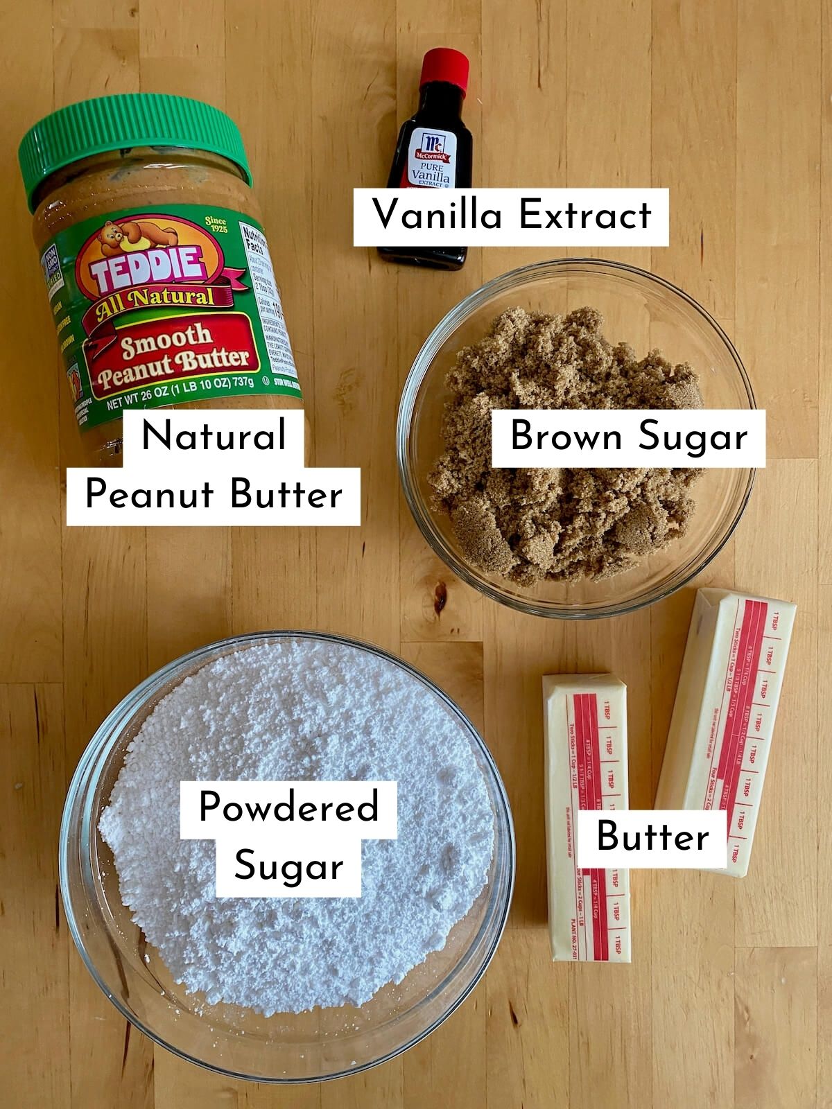 The ingredients to make no bake peanut butter fudge. Each ingredient is labeled with text stating what it is. They include natural peanut butter, vanilla extract brown sugar, powdered sugar, and butter.