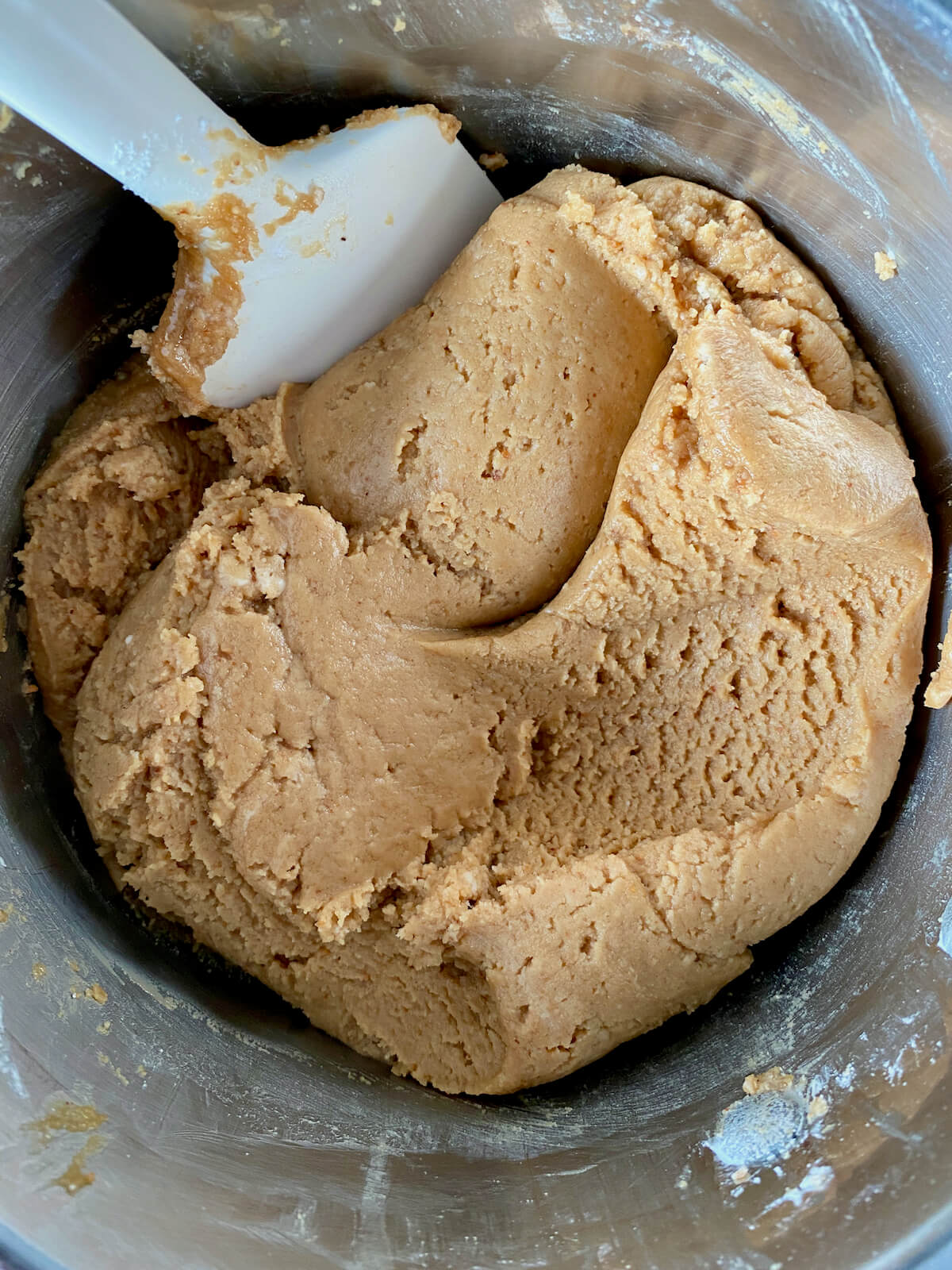 The peanut butter fudge mixture in a stainless steel pot with a rubber spatula sticking out.
