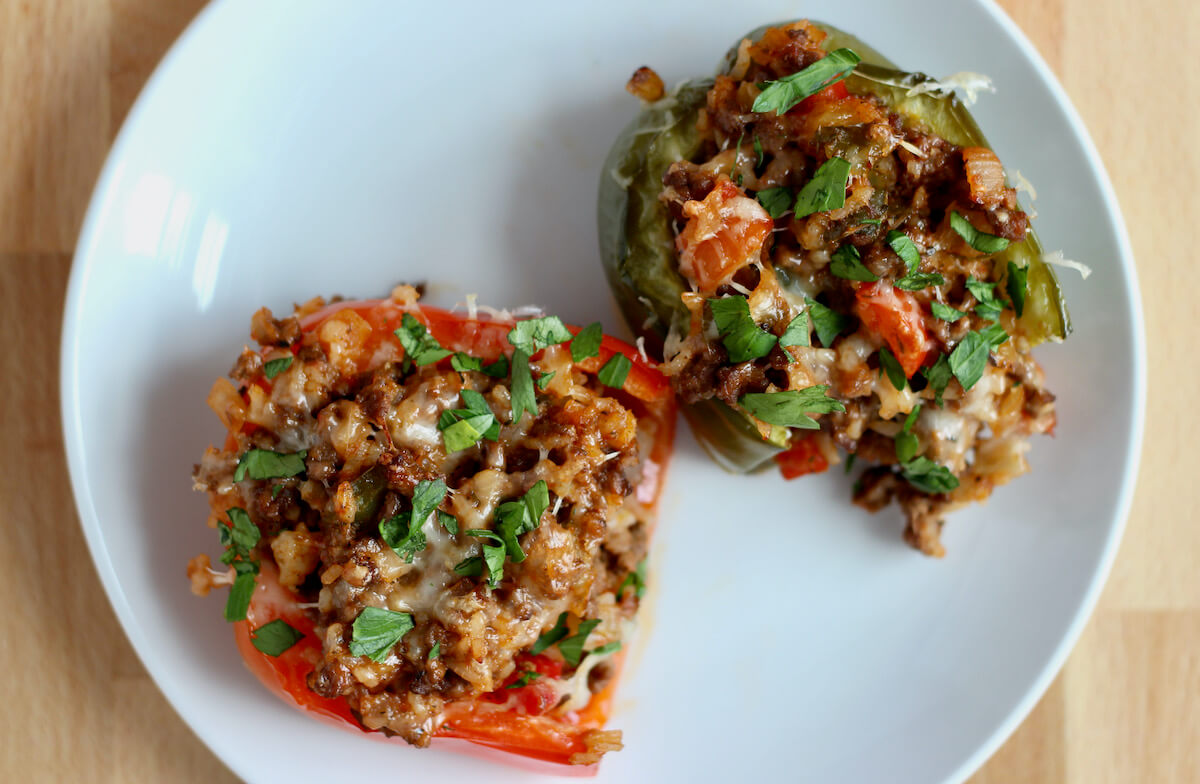 Two stuffed peppers without tomato sauce on a small white plate.