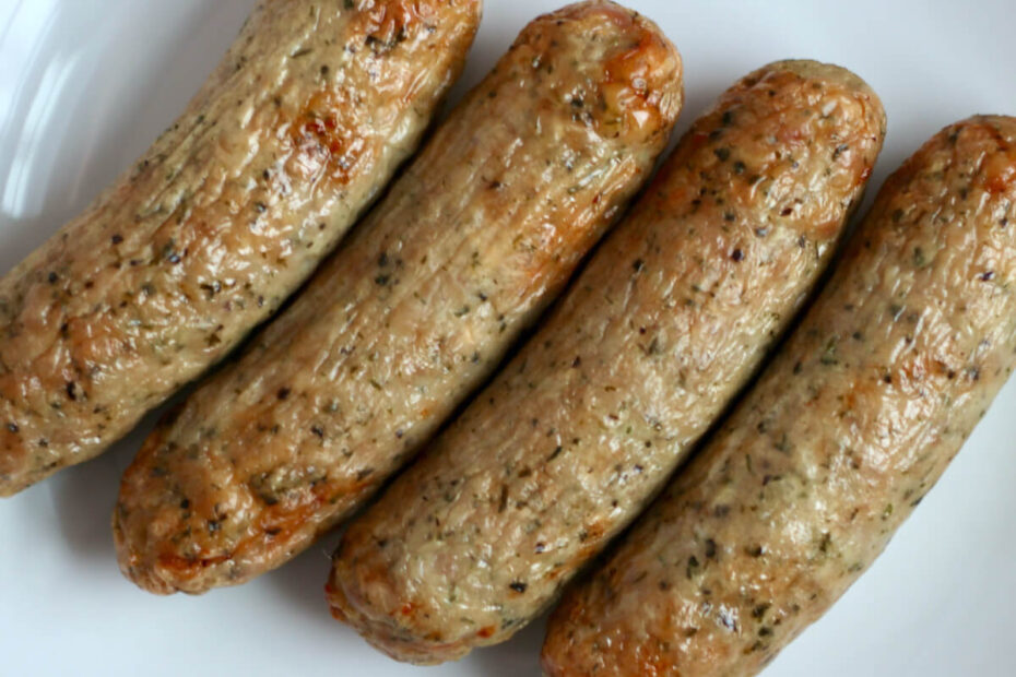 Four air fryer chicken sausages on a small white plate.