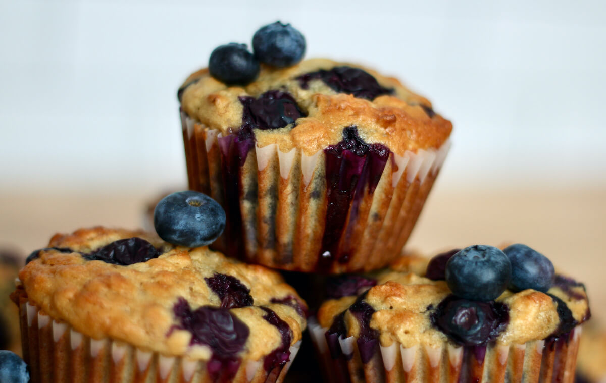 A stack of banana blueberry oatmeal muffins garnished with fresh blueberries.