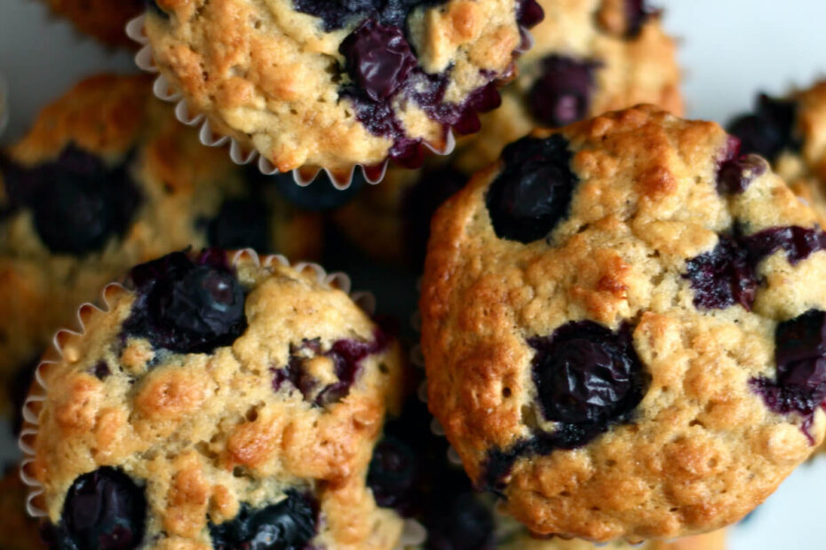 A pile of banana blueberry oatmeal muffins on a large white plate.