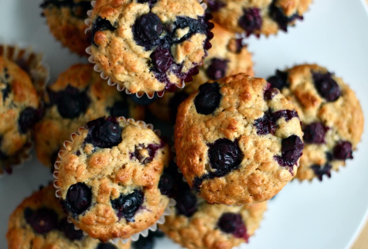 A dozen banana blueberry oatmeal muffins on a large white plate.