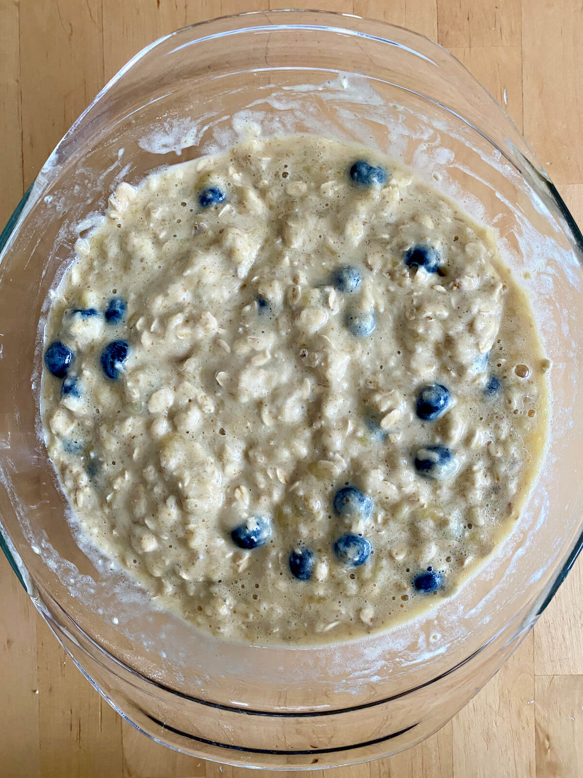 The banana blueberry oatmeal muffin batter in a glass mixing bowl.