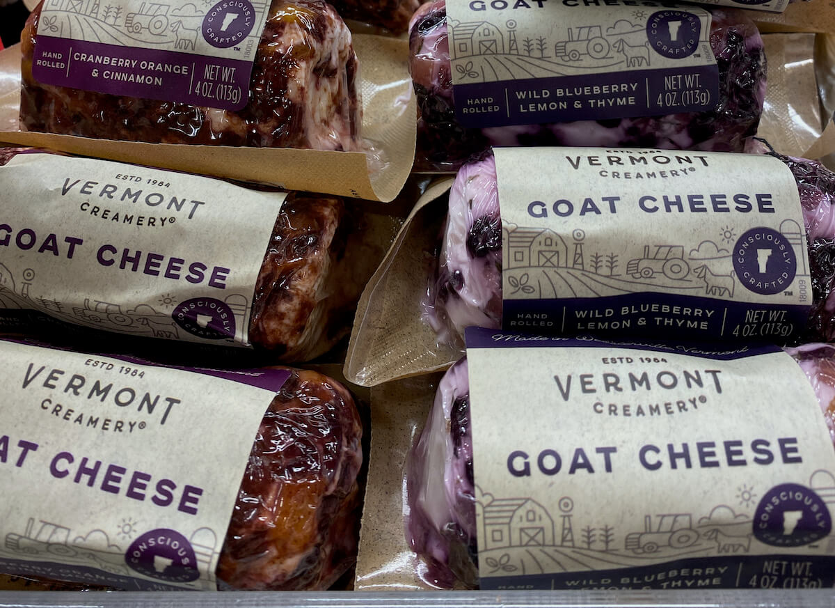 Logs of goat cheese on a grocery store shelf.